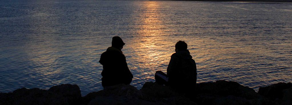 A couple sitting on rocks by the beach